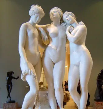 The Three Graces marble sculpture with three female figures grouped together in a museum gallery.