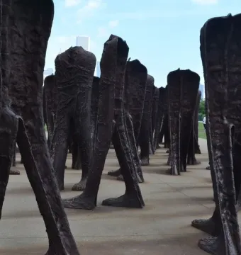 Agora sculpture with numerous dark headless human figures standing together in Grant Park