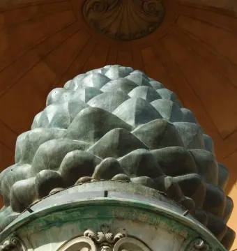 La Pigna sculpture resembling a giant green pine cone in front of a domed building