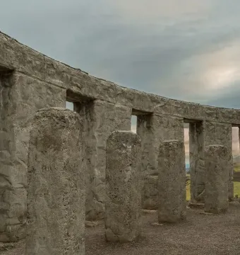 Maryhill Stonehenge, with rough concrete pillars and lintels arranged in a partial circle overlooking rolling hills and water.