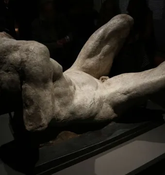 Reclining River God sculpture with a textured torso and legs on a dark base.