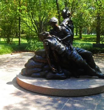 Vietnam Women\'s Memorial bronze sculpture showing two female figures tending a prone figure on a circular stone base.
