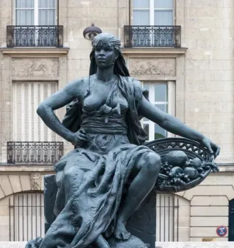Africa by Eugène Delaplanche, a dark patinated seated woman with a headscarf, flowing drapery, and a basket of fruit, resting her feet on a tortoise.