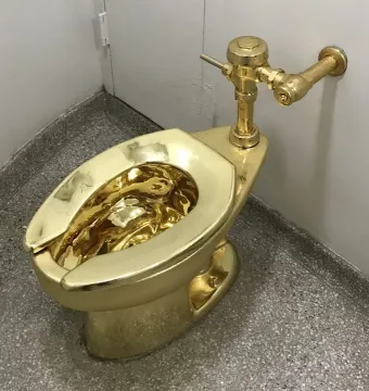 America gold toilet in a room corner with a speckled grey floor