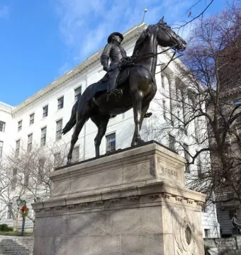 Joseph Hooker statue, a bronze equestrian monument on a stone pedestal, with a white building and bare trees behind it.