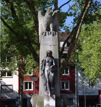 Mutter Kinzig monument with a stone eagle atop a tall shaft and a dark female figure below.