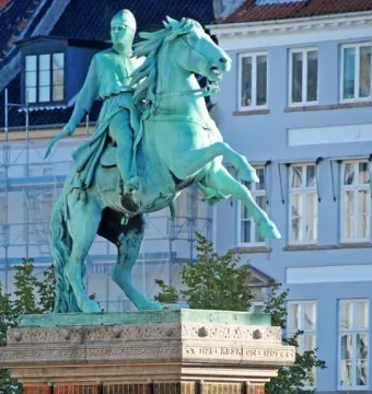 Absalon Monument, a green-patinaed equestrian statue on a brick and stone pedestal with buildings and trees behind it.