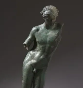 The Cleveland Apollo bronze statue with a green patina, standing on a simple base against a dark background.