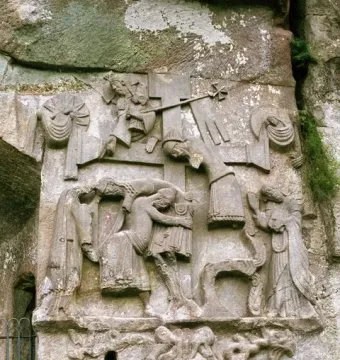 Externsteine relief showing figures around a central cross carved into a weathered rock face.