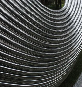 Close-up of the Infinite Wave sculpture’s reflective metallic tubes curving together outdoors.