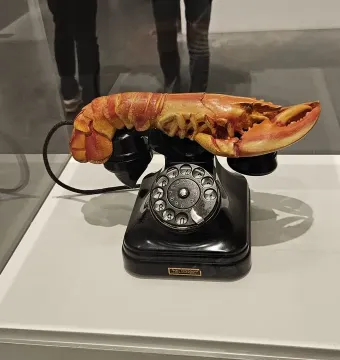 Salvador Dalí’s Lobster Telephone with a red lobster resting on a black rotary telephone inside a display case.