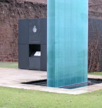 The National Police Memorial with a tall translucent teal column beside a dark memorial structure.
