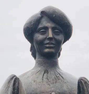 Bronze statue of Zabel Yessayan shown from the chest up, holding a book to her chest.