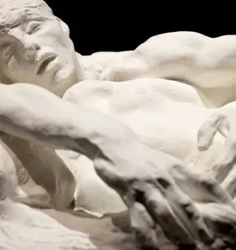 A close-up of Rodin’s Avarice and Lust showing two intertwined figures in rough white plaster against a dark background.