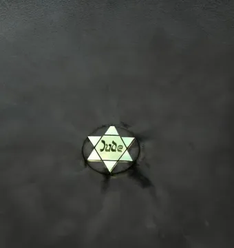 Glowing Star of David with the word Jude inscribed on a dark textured surface.