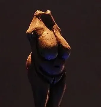 Venus of Moravany figurine with prominent breasts and enlarged abdomen on a clear display base.
