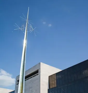 Ad Astra, a towering gold-colored abstract sculpture with star-like elements at the top against a blue sky.