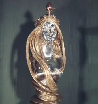 Nature sculpture by Alfons Mucha, showing a silver-faced woman\'s bust with flowing golden hair and a golden crown.
