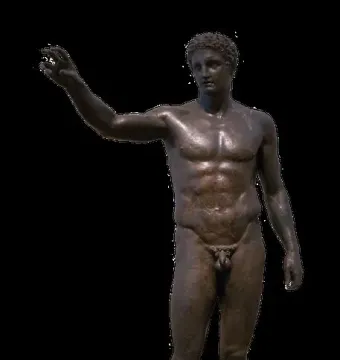 Antikythera Ephebe, a dark bronze nude male youth statue with short curly hair and one arm extended, on a light base against a black background.