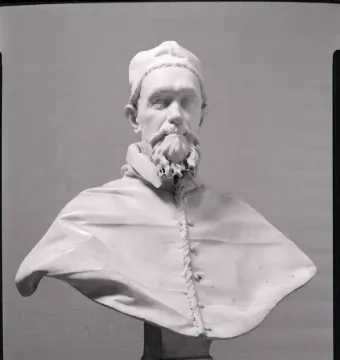 White marble bust of Pope Innocent X with a beard, mustache, and cap, shown on a decorative pedestal.
