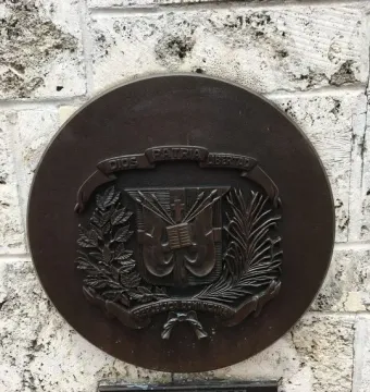 Bronze Dominican Republic coat of arms plaque on the Torch of Friendship wall.
