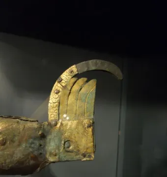 Close-up of the weathered tail section of Gallo di Ramperto, showing green corrosion and traces of a golden finish.