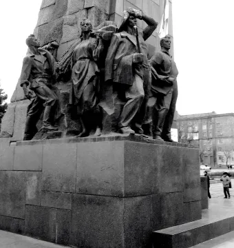The base of the Lenin Monument in Zaporizhzhia, showing sculpted figures on a granite pedestal in a public square.