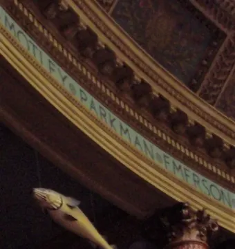 Sacred Cod fish sculpture suspended in front of an ornate frieze with engraved text.