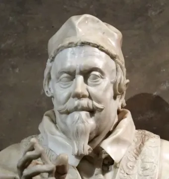 White marble bust of Pope Clement X with a mustache, pointed beard, and ornate robes, with one hand raised in a gesture.