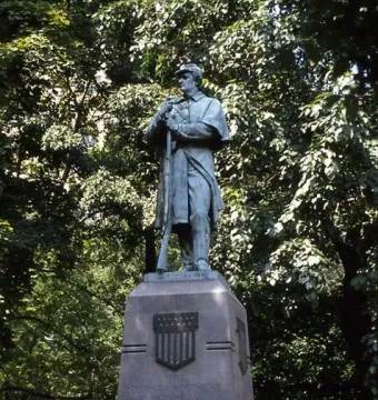 Seventh Regiment Memorial statue of a soldier holding a rifle beside a stone pedestal in Central Park