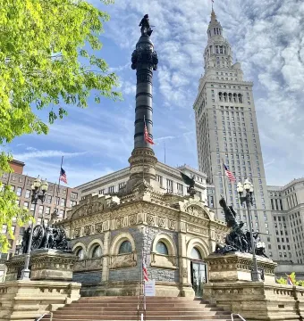 Soldiers\' and Sailors\' Monument in Cleveland with a tall granite shaft, surrounding sculptural figures, and American flags.