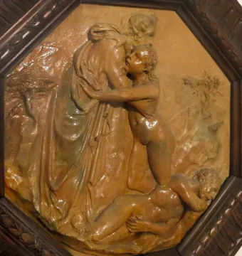 Donatello’s Creation of Eve relief in a dark octagonal frame, showing a robed figure embracing a nude figure above a reclining body.