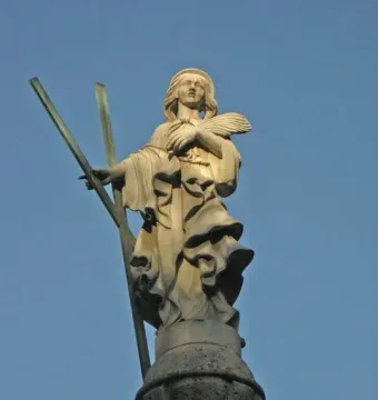 Stone statue of Santa Eulàlia with a halo, holding crossed staves and palm fronds on an ornate base.