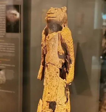 Fragmented Lion-man sculpture with an animal head and rough light-colored surface on a display base.
