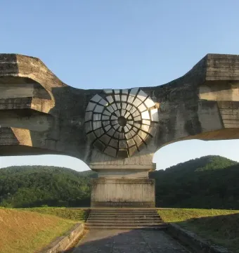Monument to the Revolution of the People of Moslavina, a brutalist concrete sculpture with wing-like forms and a central metallic disc.