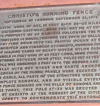 Bronze commemorative plaque for Running Fence mounted on a reddish-brown wall.