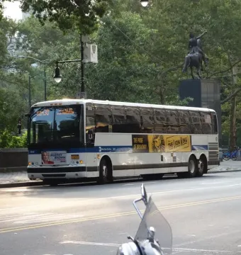 Simón Bolívar Equestrian Statue partially obscured by a large bus in front of trees.