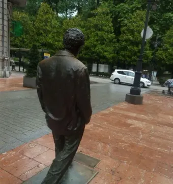 Rear view of the Woody Allen memorial bronze statue on a stone-paved sidewalk.