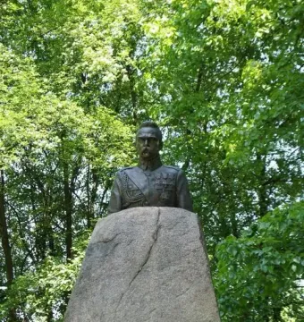 Bronze bust of Józef Piłsudski in military uniform on a rough stone pedestal with an inscription plaque.