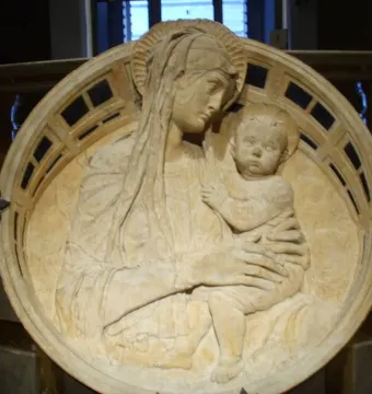 Madonna del Perdono stone relief showing a woman holding a child with halos and a decorative border