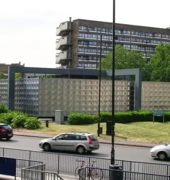 Michael Faraday Memorial beside a road, with a light-colored patterned surface and nearby landscaping.