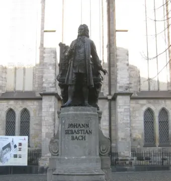 New Bach Monument statue of Johann Sebastian Bach on a stone pedestal in front of a historic church building