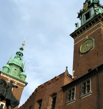 Tadeusz Kościuszko Monument, a dark equestrian statue beside a brick tower with a green spire at Wawel Castle.
