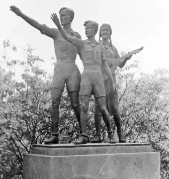Youth Monument showing three young figures on a stone pedestal, with one male figure saluting and a female figure holding a lute-like instrument.