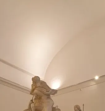 The Farnese Bull, a colossal marble group sculpture with multiple figures in a museum gallery.