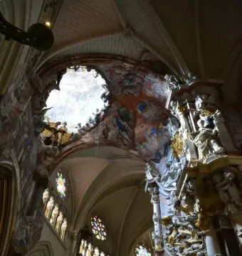 The Transparente in Toledo Cathedral, with a bright opening in the ceiling above an ornate sculpted altar and vaulted arches.