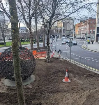Universal Links on Human Rights sculpture with a dark spherical metal form on a circular base in an urban streetscape.