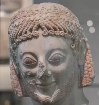 Marble head of the Rampin Rider with an archaic smile, carved curls, and a decorative leaf-pattern band.