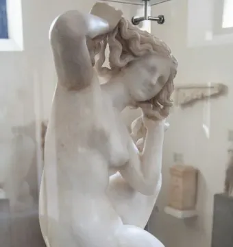 Crouching Venus marble sculpture of a crouching nude female figure displayed in a glass case