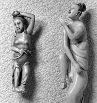 Two carved female figures, one standing with raised arms and one kneeling with a tilted-back head.